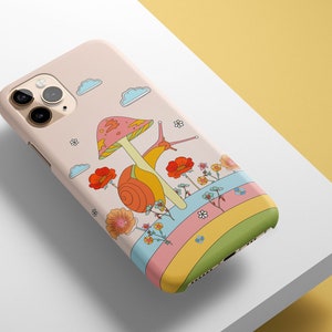 May include: A pink iPhone case with a colorful illustration of a snail on a mushroom with flowers and a rainbow.