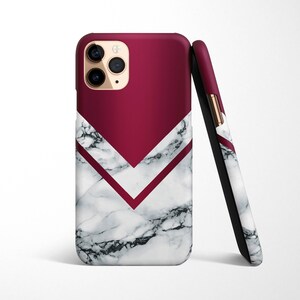 May include: A white and burgundy phone case with a marble pattern and a geometric design. The case has a raised camera bump and a gold accent.
