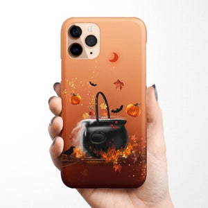 May include: A black cauldron with a red crescent moon and orange pumpkins on a phone case with a brown and orange background.