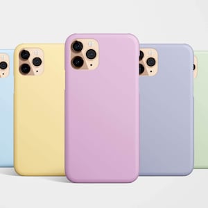 Puede incluir: Cinco fundas de teléfono de colores pastel: azul claro, amarillo, lavanda, morado y verde claro. Cada funda tiene un recorte para la cámara con tres lentes y un flash. Las fundas están dispuestas en fila.