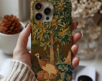 Puede incluir: Una funda de teléfono con un diseño de tapiz que representa un faisán, árboles y follaje en tonos marrones, verdes y amarillos. La funda tiene un recorte para la cámara y está sujeta en la mano de una persona.