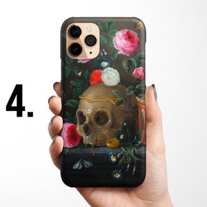 Pode incluir: Uma capa de telefone com uma pintura de uma caveira, flores e um pequeno rel&oacute;gio de areia. A caveira &eacute; cercada por flores rosa, brancas e vermelhas. O fundo &eacute; verde escuro e preto.
