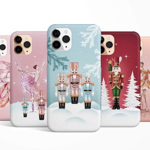 Puede incluir: Cuatro fundas de teléfono diferentes con un tema navideño de invierno. Las fundas presentan una bailarina, un cascanueces y una escena de bosque nevado. Las fundas están disponibles en rosa, azul, rojo y melocotón.