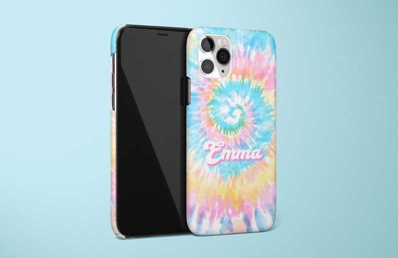 May include: A smartphone and a phone case with a tie-dye design in shades of blue, pink, and yellow. The name "Emma" is printed on the case in a pink and white font. The phone is black.