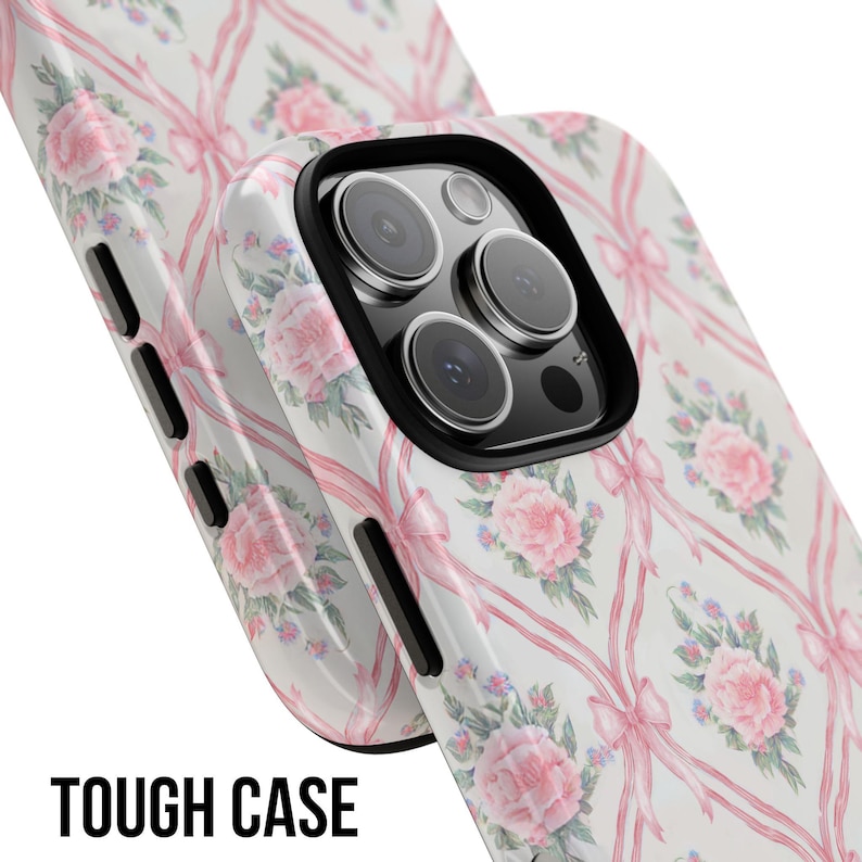 May include: A white phone case with a pink and white floral pattern and pink bows. The case has a cutout for the camera lens. The text "TOUGH CASE" is printed on the bottom of the image.
