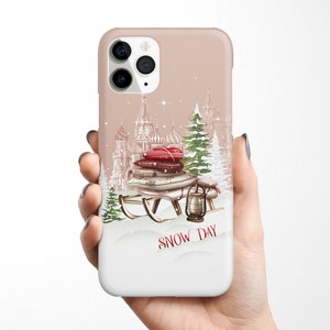 May include: A phone case with a winter scene featuring a sled with gifts, a lantern, and a snowy cityscape. The text "SNOW DAY" is printed on the case.