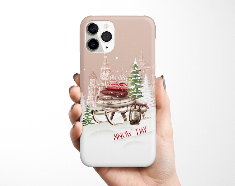 May include: A phone case with a winter scene featuring a sled with gifts, a lantern, and a snowy cityscape. The text "SNOW DAY" is printed on the case.