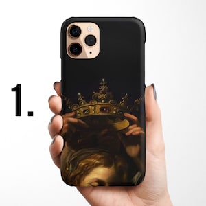 Pode incluir: Uma capa preta para iPhone com uma coroa dourada e uma pintura de uma pessoa usando a coroa. A capa tem um recorte para a lente da c&acirc;mera.