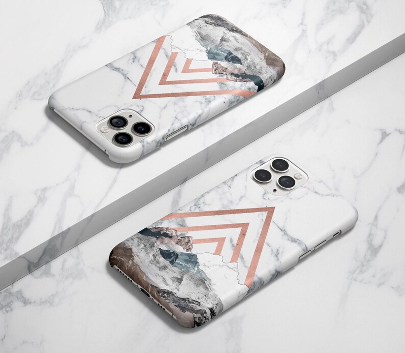 K&ouml;nnte beinhalten: Zwei wei&szlig;e iPhone-H&uuml;llen mit Marmormuster und geometrischen Designs in Ros&eacute;gold. Eine H&uuml;lle hat ein Bergketten-Design und die andere ein schlichtes geometrisches Design.