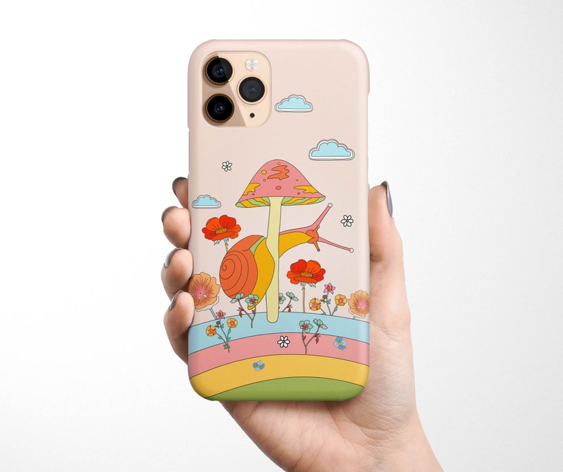 May include: A pink and white iPhone case with a cartoon snail and mushroom design. The snail is crawling on a mushroom with a pink and white cap. The background is a rainbow with flowers and clouds.