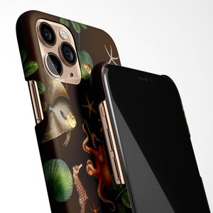 May include: A black phone case with a gold trim and a colorful illustration of sea life, including an octopus, a seahorse, and a fish. The case is designed for an iPhone.