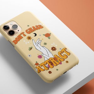 Może przedstawiać: Ż&oacute;łte etui na iPhone'a z kwiatowym wzorem i tekstem "Don't Chase, Attract" w retro czcionce.