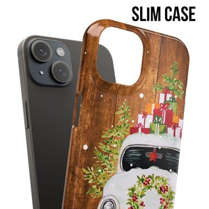 May include: A phone case with a woodgrain background and a white vintage car with a pile of wrapped presents on top. The car has a red star on the front and a wreath of holly on the front bumper.
