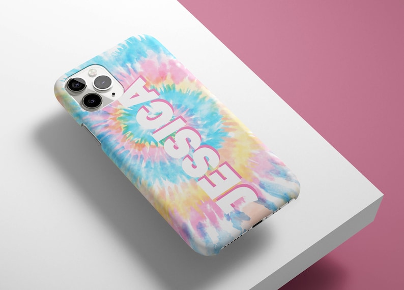 May include: A white iPhone case with a tie-dye pattern in shades of blue, pink, and yellow. The name "Jessie" is printed in white on the case.