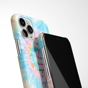May include: Two iPhone cases, one with a tie-dye pattern and the other black. The tie-dye case has a pink, blue, and yellow swirl pattern. The black case has a silver trim.