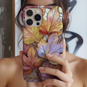 Puede incluir: Una funda de teléfono inteligente con un diseño de hojas de otoño colorido. La funda muestra un patrón de hojas estilizadas en tonos de amarillo, naranja, morado y dorado, con un acabado brillante. La funda tiene un recorte multicámara.