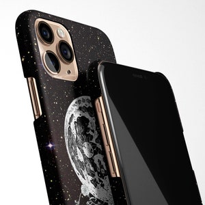 May include: A black phone case with a glittery starry night design and a close-up of a moon with craters. The case has a gold trim and a black phone screen.