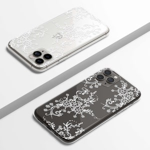 May include: Two clear phone cases with a white floral design. The cases are for an iPhone with a triple lens camera.