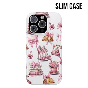 Pode incluir: Capa de telefone fina branca com um padr&atilde;o repetido de la&ccedil;os rosa, saltos altos, croissants, x&iacute;caras de ch&aacute; e um telefone vintage. A capa tem as palavras "SLIM CASE" em preto.