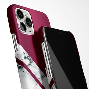 May include: A burgundy and white marble phone case with a black phone inside. The case has a geometric design with a white marble pattern and a burgundy background.