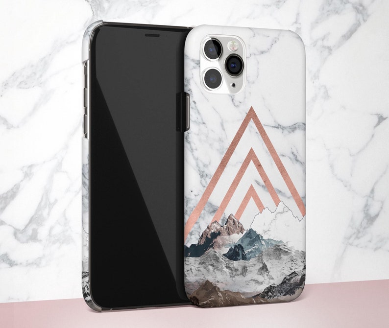 K&ouml;nnte beinhalten: Eine wei&szlig;e und ros&eacute;goldene Handyh&uuml;lle mit Marmormuster und einem Bergpanorama-Design. Die H&uuml;lle hat einen Ausschnitt f&uuml;r die Kamera.