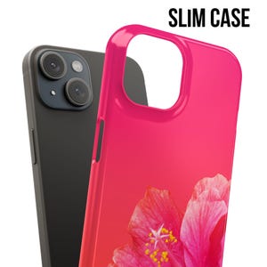 May include: A pink phone case with a hibiscus flower design. The case is slim and has a gradient effect from dark pink to light pink.