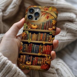 May include: A phone case featuring a detailed illustration of a bookshelf with pumpkins and autumn leaves. The case has a warm color palette of browns, oranges, and greens, creating a cozy, seasonal aesthetic. The design includes a three-dimensional effect.