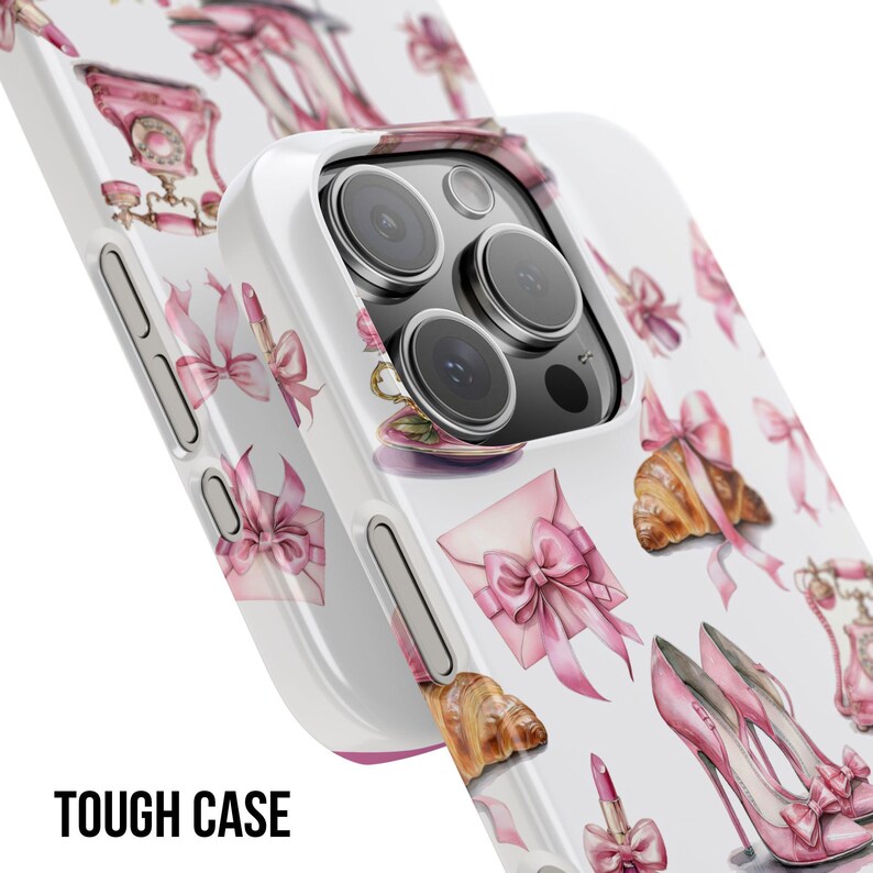 Pode incluir: Capa de telefone branca com um padr&atilde;o repetido de la&ccedil;os rosa, saltos altos, croissants e batom. A capa tem um design protetor e as palavras "TOUGH CASE" s&atilde;o impressas em preto na parte inferior.