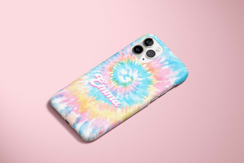 May include: A colorful phone case with a tie-dye design in shades of blue, pink, yellow, and white. The name "Emma" is printed in a cursive font across the case. The phone case has a camera and flash.