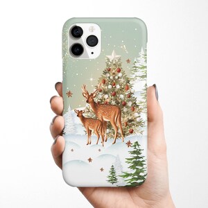 May include: A green and white phone case with a winter scene featuring a Christmas tree, two deer, and snowflakes.