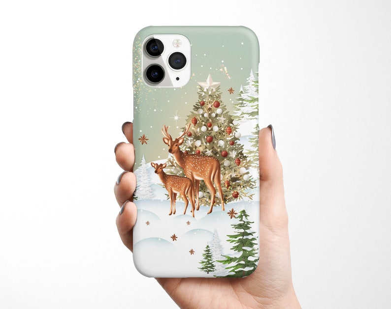 May include: A green and white phone case with a winter scene featuring a Christmas tree, two deer, and snowflakes.