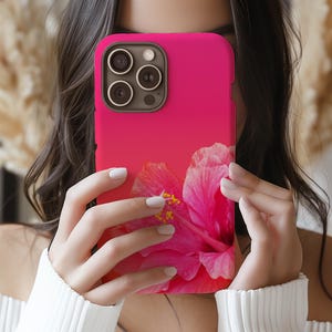 May include: A pink and red phone case with a hibiscus flower design. The case has a gradient color scheme and a cutout for the camera lens.