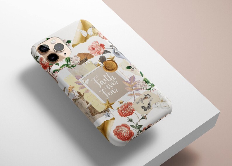 Op de afbeelding: Een witte iPhone-hoes met een collage-ontwerp met bloemen, vlinders, sterren en de tekst "Faith over Fear".