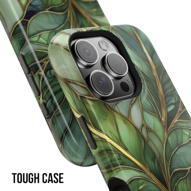 May include: A close-up of two phone cases with a green and gold leaf design. The cases have a glossy finish and the text "TOUGH CASE" is printed in white at the bottom. The phone cases have a black border around the camera.