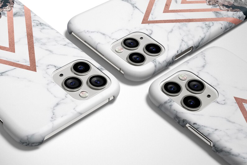 K&ouml;nnte beinhalten: Drei wei&szlig;e iPhone-H&uuml;llen mit Marmormuster und geometrischen Designs in Ros&eacute;gold. Die H&uuml;llen haben eine erh&ouml;hte Kamerabuckel mit drei Objektiven.