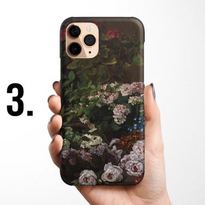 Pode incluir: Uma capa de telefone com um design floral que apresenta uma variedade de flores em tons de rosa, roxo e azul. A capa &eacute; preta e tem um recorte para a c&acirc;mera.