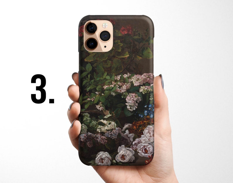Pode incluir: Uma capa de telefone com um design floral que apresenta uma variedade de flores em tons de rosa, roxo e azul. A capa &eacute; preta e tem um recorte para a c&acirc;mera.
