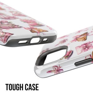 Pode incluir: Duas capas de telefone brancas com um padr&atilde;o rosa e dourado de la&ccedil;os, presentes e batom. As capas t&ecirc;m uma borda preta e as palavras "TOUGH CASE" em letras pretas em negrito na parte inferior.