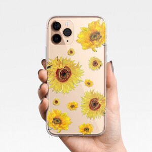 May include: Clear phone case with a design of yellow sunflowers on a white background. The case is designed for an iPhone.