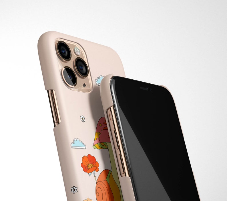May include: A pink phone case with a mushroom and snail design. The case has a gold trim and a black phone screen.