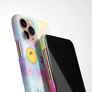 May include: Two phone cases, one with a tie-dye pattern and a smiley face, and the other with a black screen.