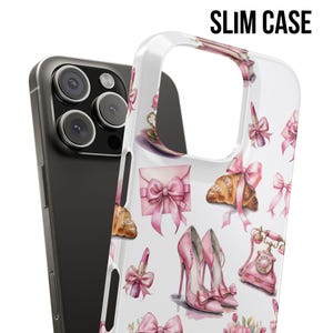 Pode incluir: Uma capa de telefone fina e transparente com um padr&atilde;o de la&ccedil;os rosa, saltos altos, croissants e batom. A capa &eacute; mostrada ao lado de um telefone preto. O texto "SLIM CASE" est&aacute; impresso no topo.