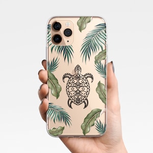 May include: A clear phone case with a gold background and a black and white geometric turtle design. The case is decorated with green palm leaves.