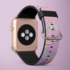 Puede incluir: Una banda de reloj Apple de color rosa y blanco con un diseño de arcoíris y un ajolote de dibujos animados. La banda está hecha de cuero y tiene una hebilla negra.