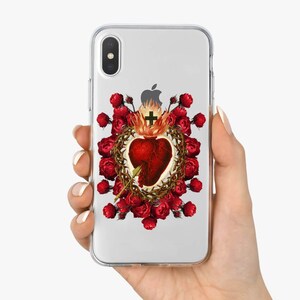 May include: A clear phone case with a design of a red heart with thorns and a cross, surrounded by red roses. The design is a vintage illustration.