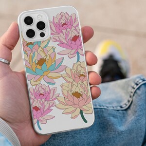 May include: A white iPhone case with a floral design featuring pink, yellow, and blue water lilies. The case has a clear back and a white border.