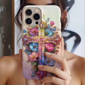 May include: A phone case featuring a colorful cross design with pink, blue, and gold floral accents. The case has a soft gradient background and a detailed, artistic rendering of the cross and flowers.