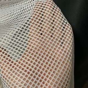 Puede incluir: Tela de malla blanca con un patr&oacute;n de cuadr&iacute;cula fina y uniforme. La tela es suave y flexible, con una superficie ligeramente texturizada.