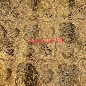 May include: Gold fabric with a black and brown damask pattern. The fabric has a subtle sheen and a textured surface.