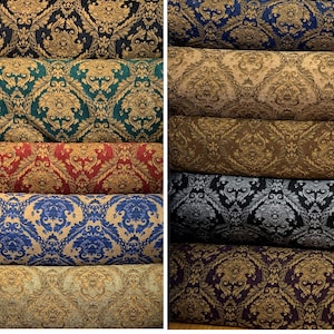 Puede incluir: Rollos de tela con patrones de damasco en varios colores. Las telas muestran un dise&ntilde;o floral detallado en tonos de azul, verde, rojo, dorado y negro, adecuado para tapicer&iacute;a o cortinas.